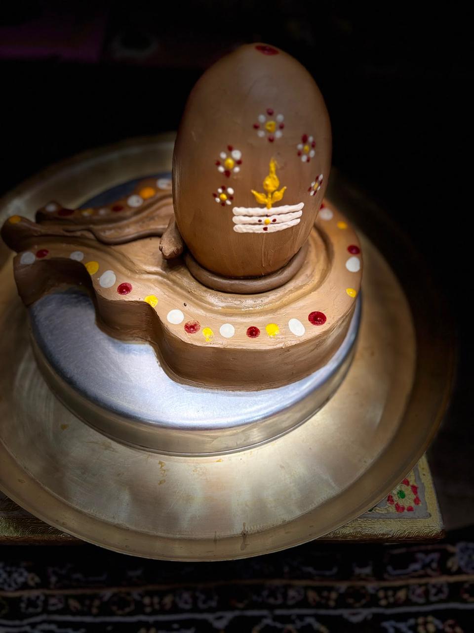 Earthen Shiva lingam decorated with sacred markings.
